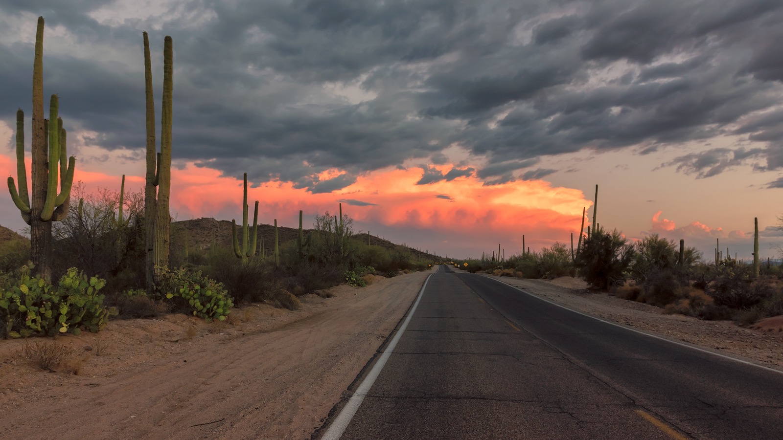 2-lane country road at sunset with saguaros
